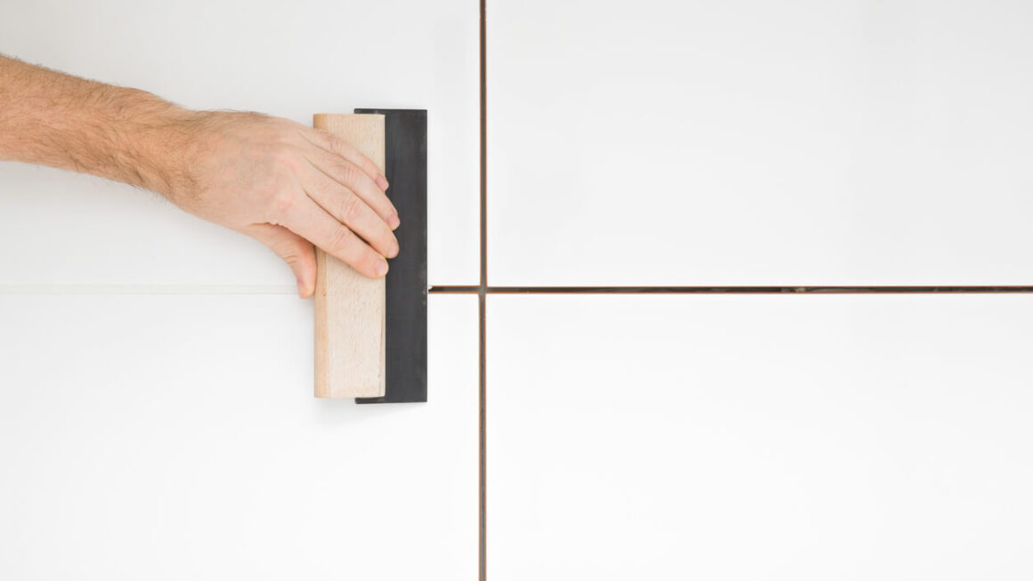 Imagem de uma pessoa assentando porcelanato.
