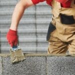 Profissional assentando blocos estruturais em obra