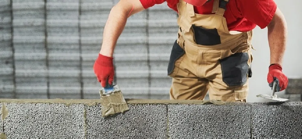 Profissional assentando blocos estruturais em obra