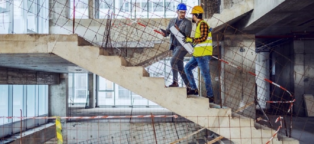 Profissionais da construção em uma escada em construção com folhas representando o cálculo de escada