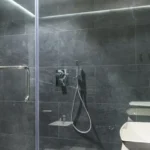 Imagem de um banheiro, com um box de vidro transparente