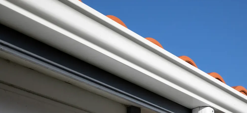 Imagem de uma calha branca instalada sob o telhado de uma casa