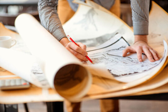 Uma pessoa está desenhando em uma folha de papel com um lápis, concentrada em sua criação.