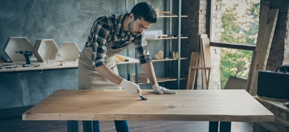 Profissional aplicando verniz para madeira em uma oficina com pincel