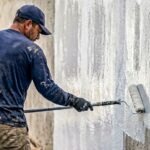 Profissional da construção impermeabilizando parede externa em obra