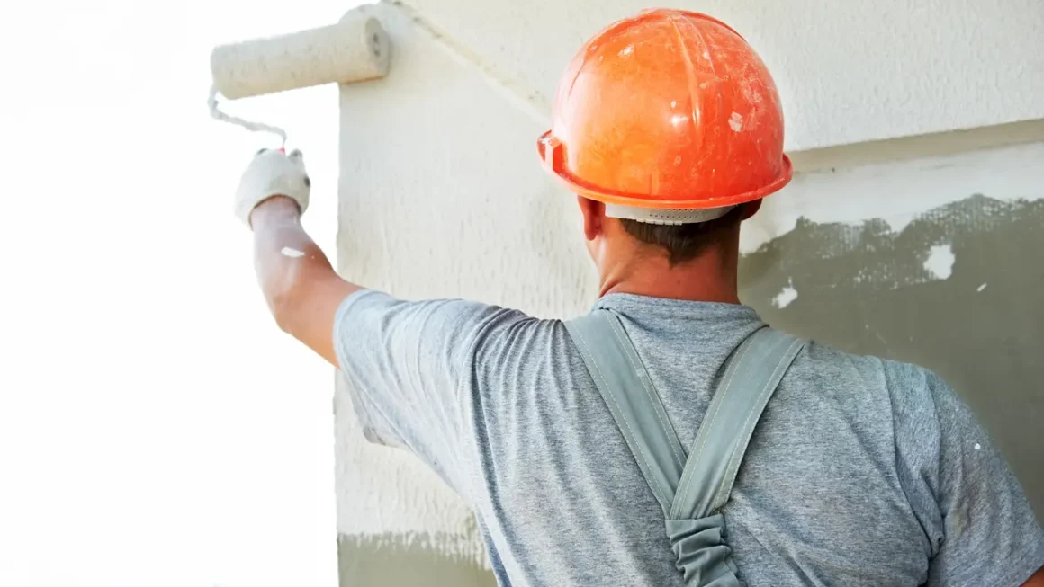 Imagem de um homem pintando uma parede com um rolo de tinta.
