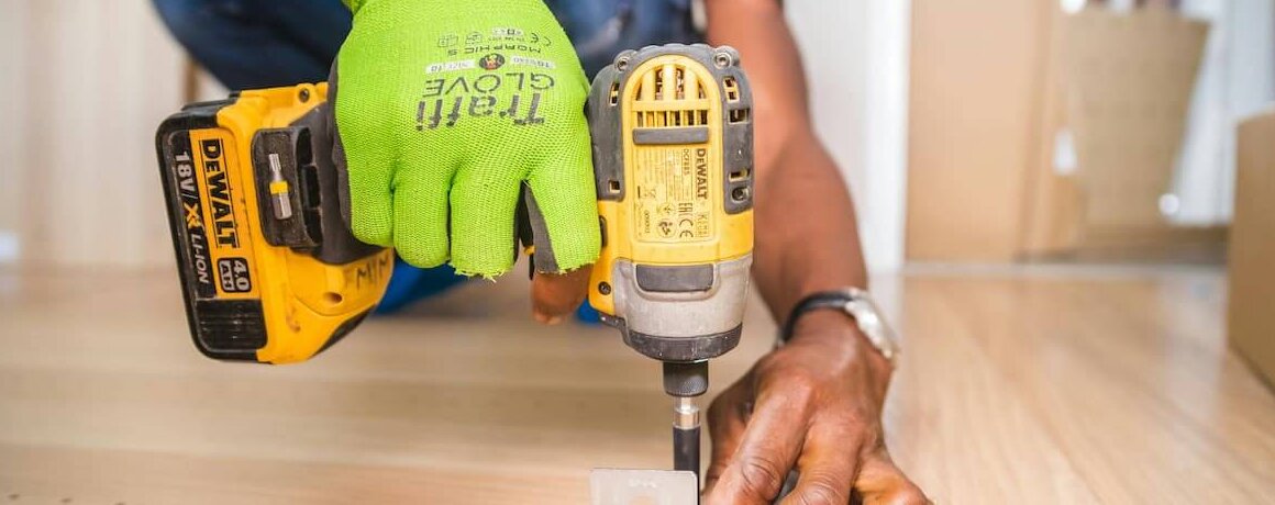 Profissional com parafusadeira em etapa da obra.