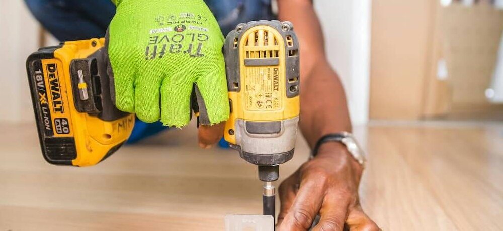 Profissional com parafusadeira em etapa da obra.