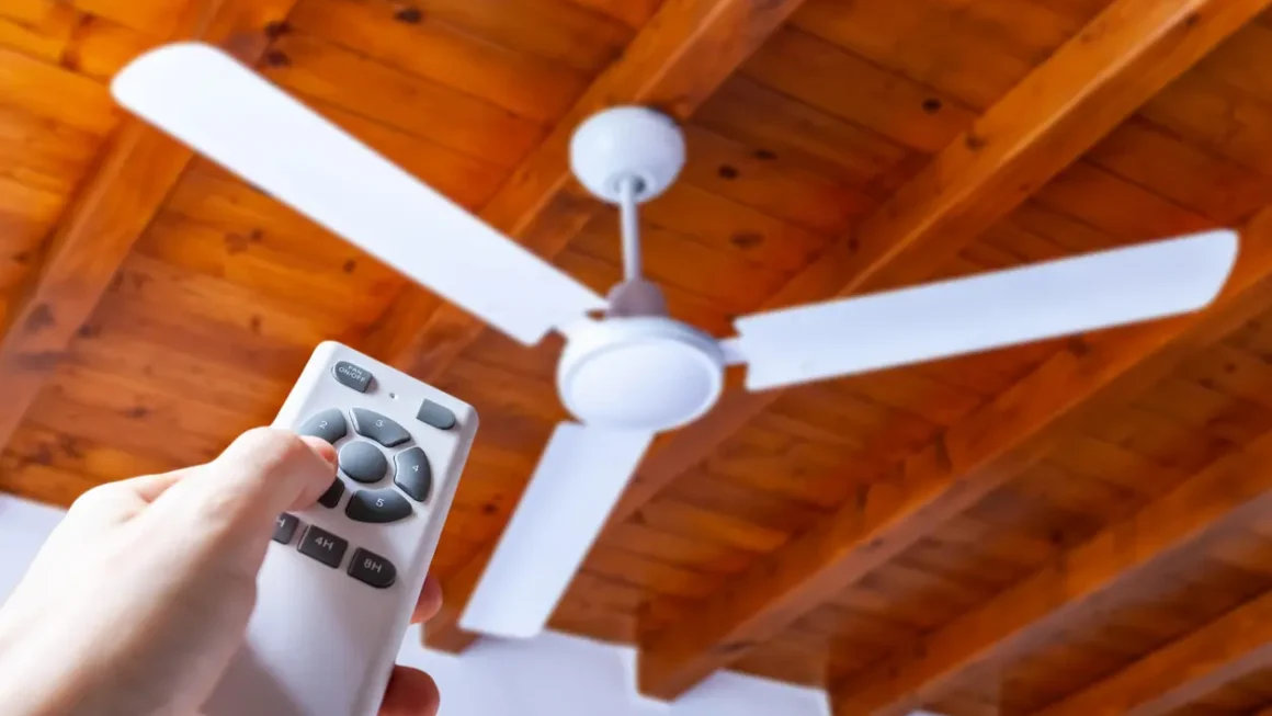 Pessoa usando um controle remoto para ligar ou ajustar um ventilador de teto.