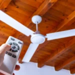 Pessoa usando um controle remoto para ligar ou ajustar um ventilador de teto.