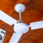 Pessoa usando um controle remoto para ligar ou ajustar um ventilador de teto.