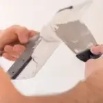 Imagem de uma pessoa aplicando massa acrílica no teto.
