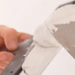 Imagem de uma pessoa aplicando massa acrílica no teto.