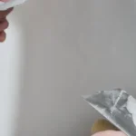 Imagem de uma pessoa fazendo reboco de parede.