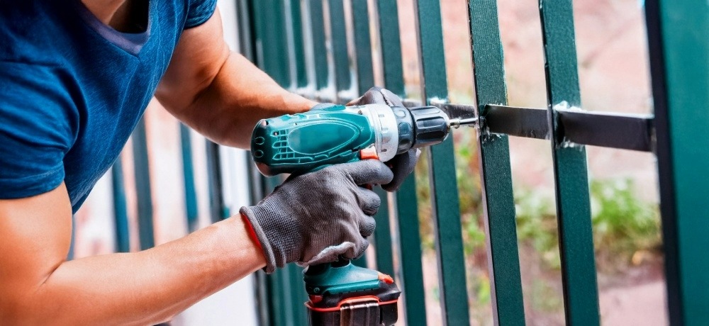 Profissional usando parafusadeira em portão de ferro
