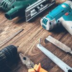 Diferentes ferramentas elétricas e manuais dispostas em uma bancada de madeira