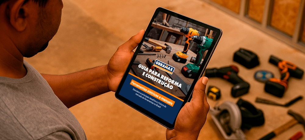 Pessoa segurando um tablet com a capa do Guia para Reforma e Construção da Obramax sobre ferramentas