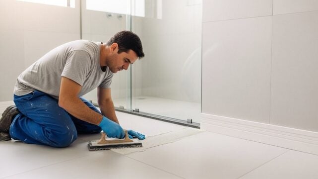 Profissional aplicando rejunte no banheiro