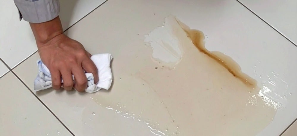 Pessoa tentando tirar mancha de piso cerâmico