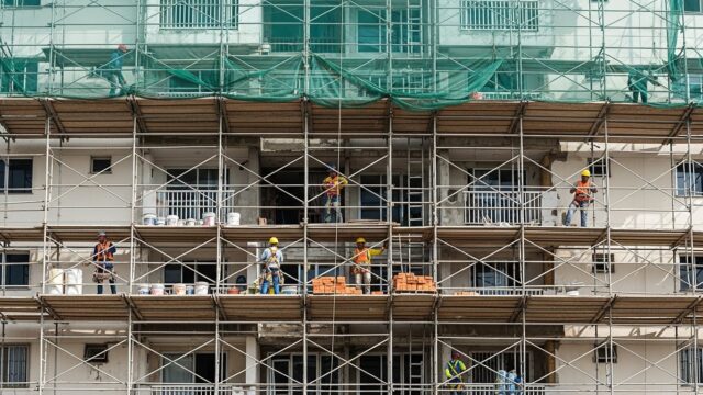 Profissionais de construção realizando alteração em fachada de condomínio